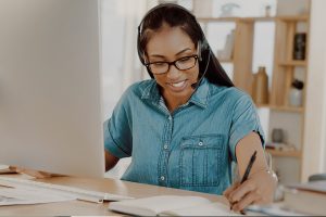 young businesswoman wearing headset and working on a computer at home