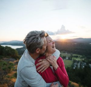 couple hugging and laughing on top of mountain