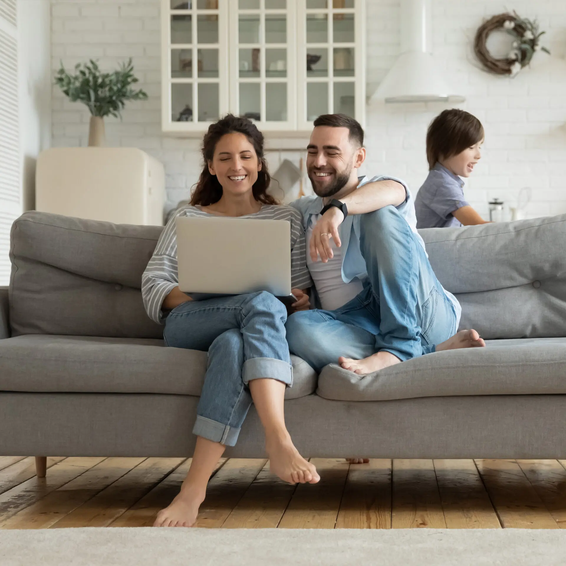 parents sit on sofa using laptop