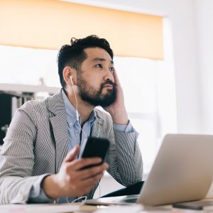 man listening to podcasts and making notes on the computer