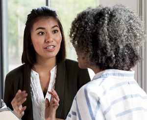 female manager and female employee stand in the conference room talking