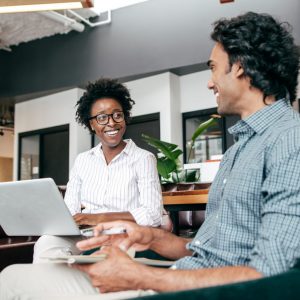 woman with laptop talking with a man in an office