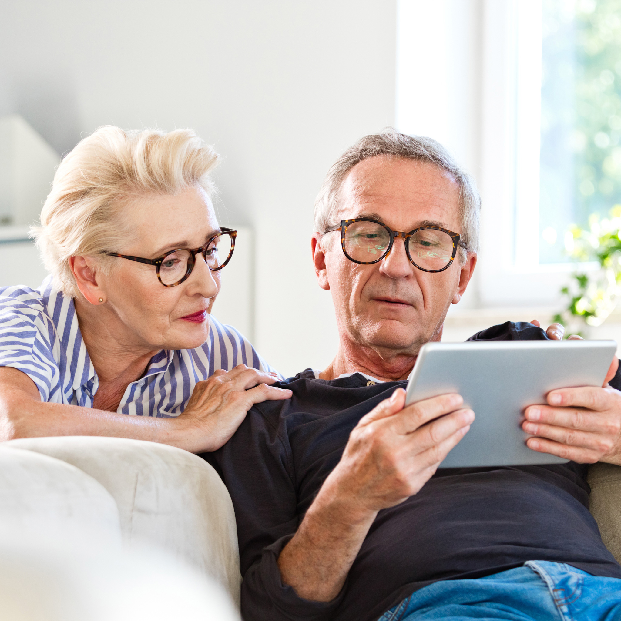senior couple with glasses staring at tablet