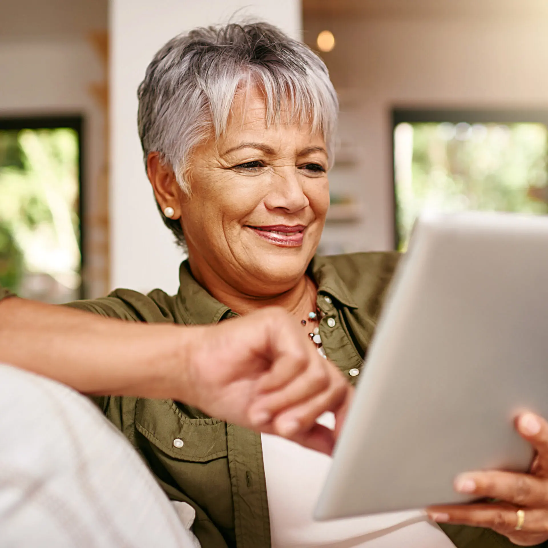 older woman relaxing on the sofa with her tablet at home