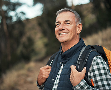 man smiling while hiking with backpack