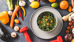 healthy food and dumbbells laid out on counter