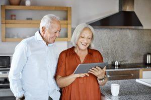 older couple using digital tablet by kitchen counter