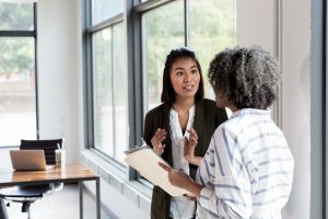 female manager and female employee stand in the conference room talking