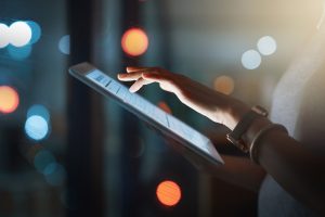 businesswoman using a digital tablet while working late