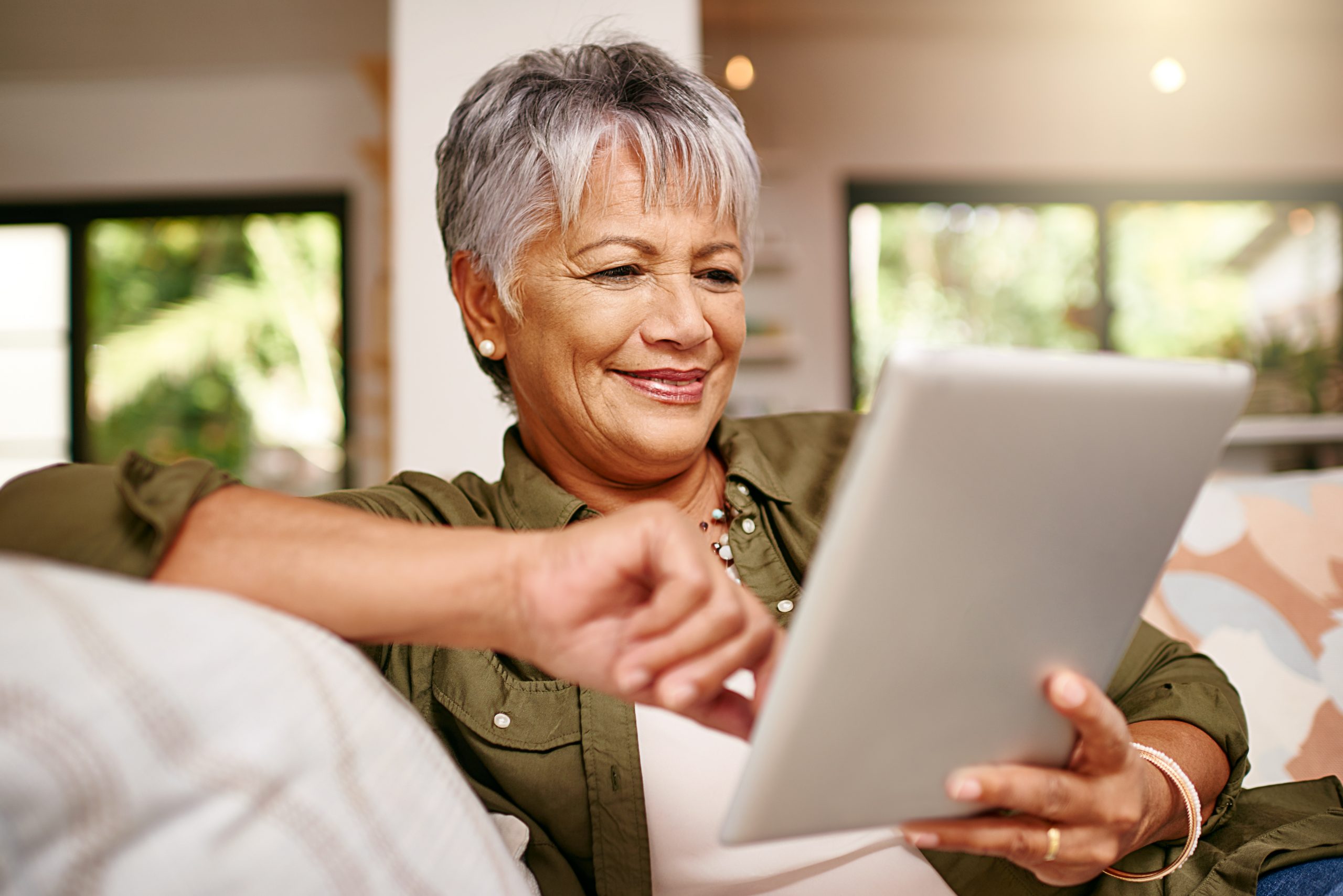 older woman relaxing on the sofa with her tablet at home