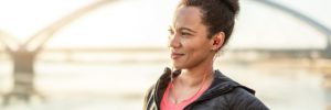 Woman in workout clothes and headphones near a bridge