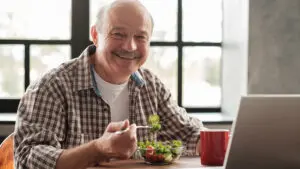 Man eating salad at computer