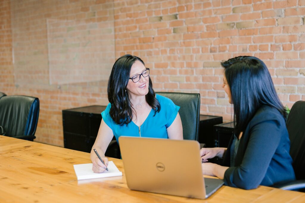 Corporate health coaching session between two women in a workplace setting, discussing employee wellness goals.