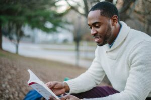 Becoming a Corporate Wellness Coach – Learning and Growing Man sitting outdoors reading a book as part of his path to becoming a corporate wellness coach