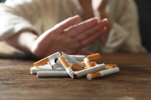 Hand refusing a pile of broken cigarettes, representing employer tobacco cessation programs