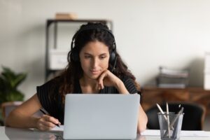 FocusedFemaleAdultStudentInHeadphonesUsingLaptopAttendingOnline | Avidon Health health coach platforms