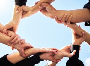 Hands joined in a circle symbolizing teamwork and support within employee wellness programs.