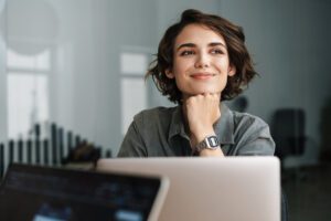 Case Study: Powering Behavior Change Through the TTM 4 A smiling woman using a laptop, representing personal growth through digital health coaching and wellness tools.