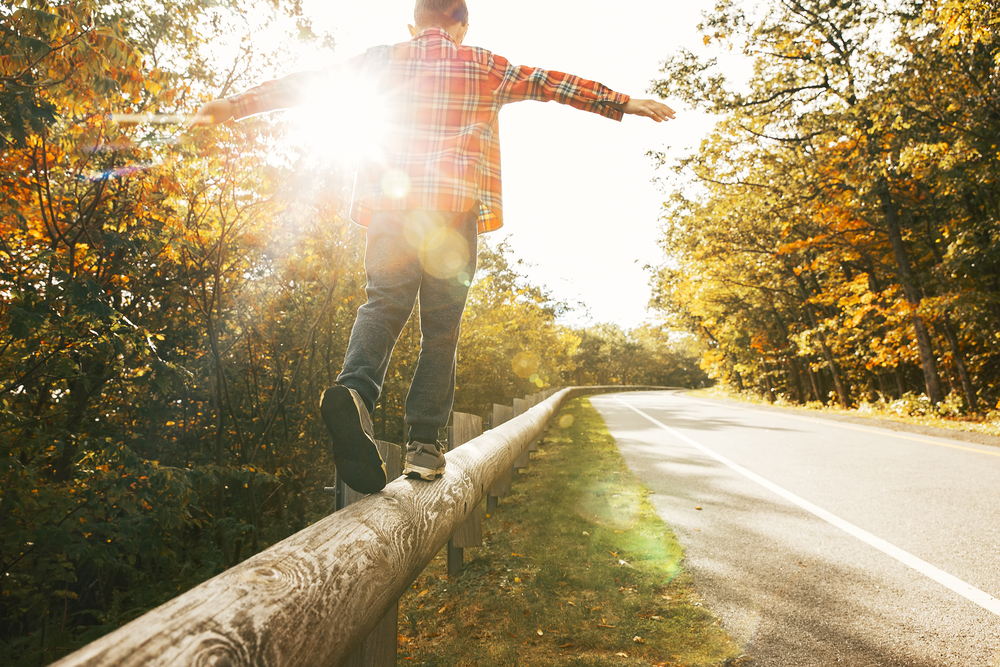 CBT In Action: From Avoidance To Breakthrough 1 Person balancing on a guardrail during a fall day, representing CBT for wellness through balance and mindful decision-making.