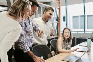 Group of professionals collaborating around a laptop in a modern office, symbolizing strategic planning for employee wellness programs.