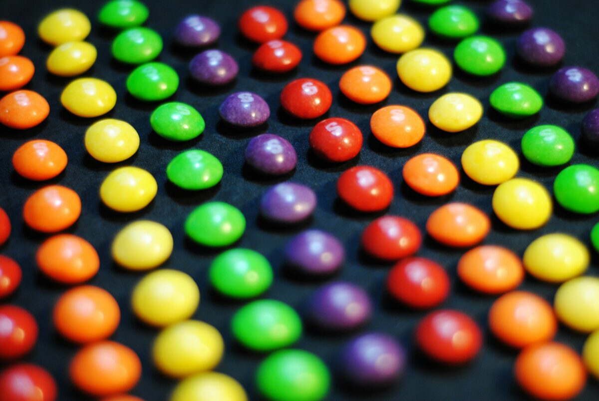 Colorful candies arranged in rows, featuring red, orange, yellow, green, and purple.