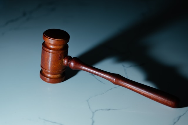 A wooden judge’s gavel resting on a marble surface, symbolizing legal and compliance issues.