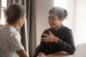 Two women engaged in a supportive conversation during a health and wellness coaching session.