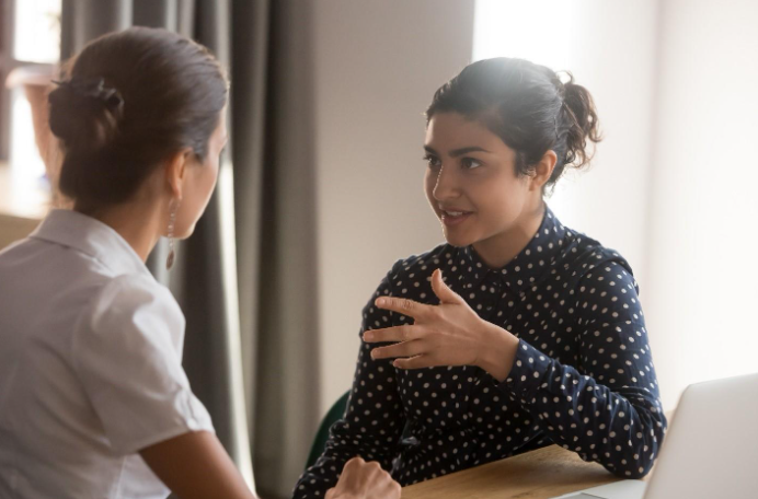 Two women engaged in a supportive conversation during a health and wellness coaching session.