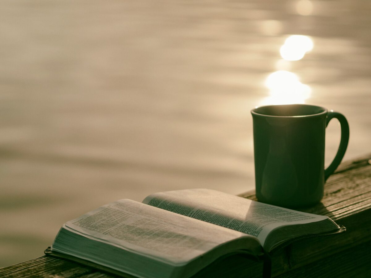 A calming moment with a book and coffee by the water, representing simple self-care habits that support mental health