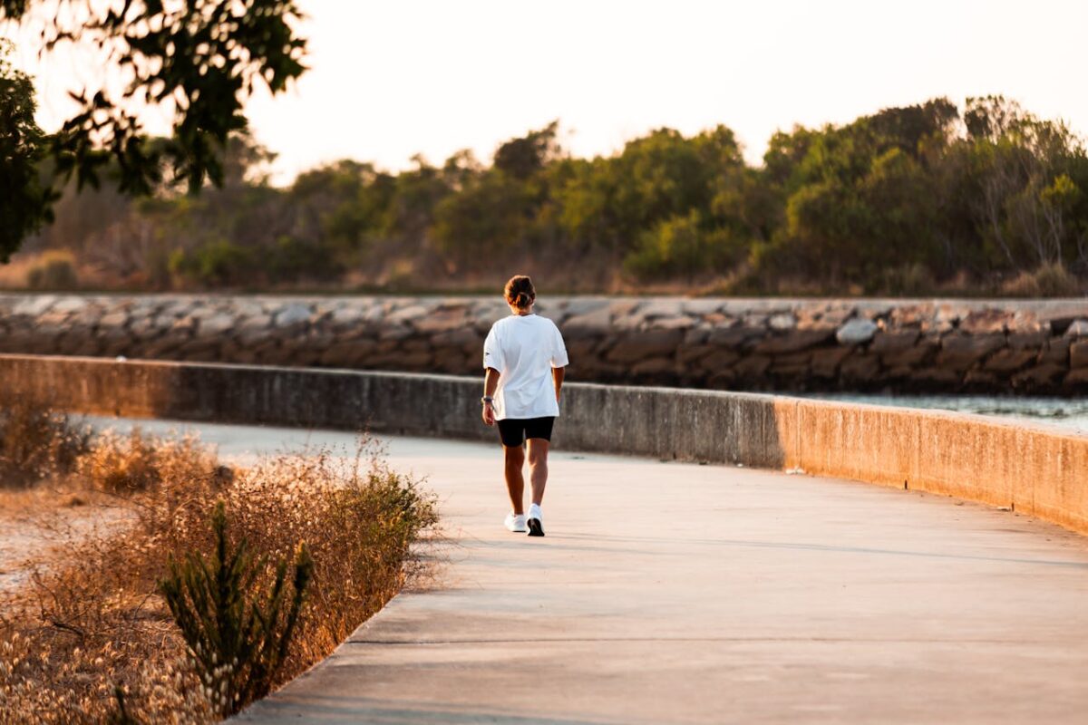 Walking a sunlit path by the water—symbolizing a health coach journey built on small, steady steps