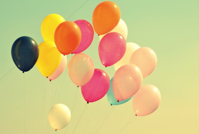 Colorful balloons against a soft sky, celebrating small wins on a health coach journey.