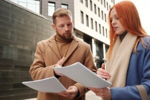 Employees discussing documents outside an office building as part of a conversation on how to improve employee morale.