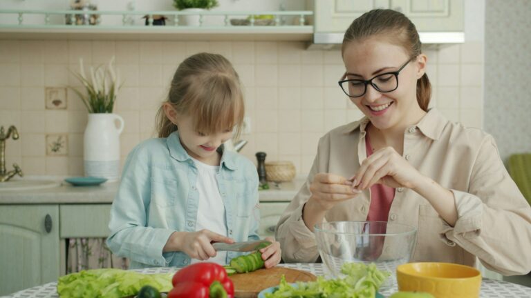 Mother and daughter preparing vegetables together in a bright kitchen, representing modeling healthy habits for kids.