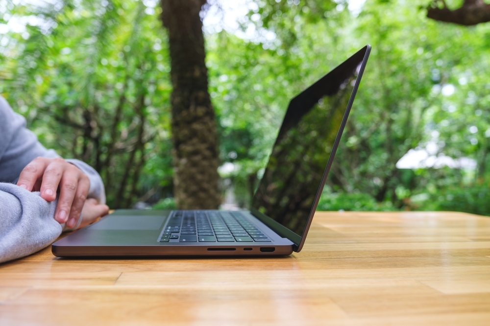 Remote employee wellness program Person working on a laptop outdoors while working remotely