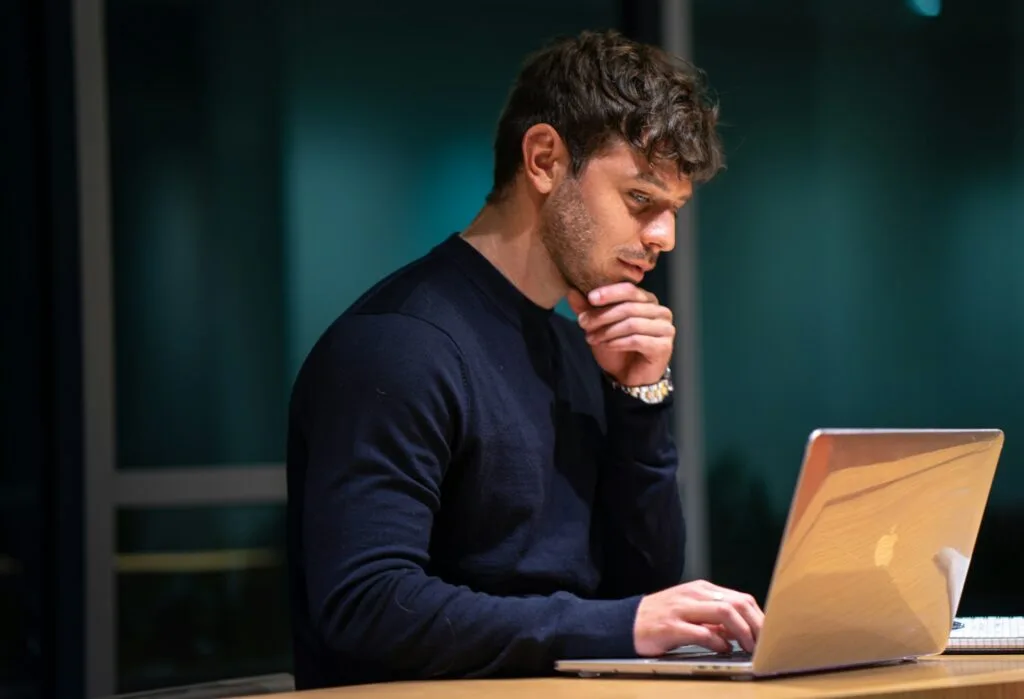Man reflecting on drinking habits at a laptop while working to drink less without quitting social life