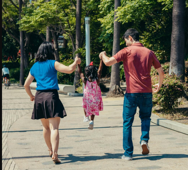 Family walking together outdoors on a sunny day, representing moving forward in life as mindset and habits become easier and more natural.