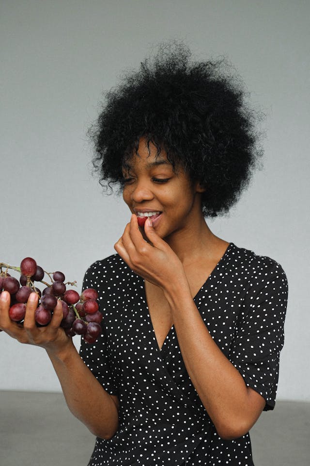 Woman eating grapes as part of a normal routine, showing how healthy eating habits can become part of everyday life
