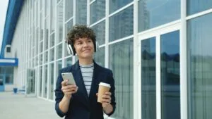 Professional walking outside with coffee and phone, showing how daily movement habits happen during normal routines
