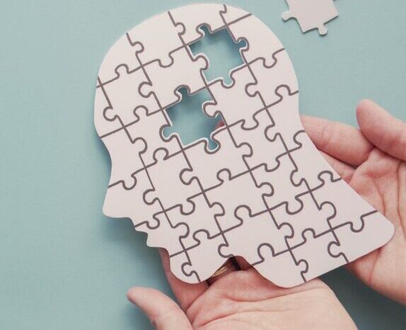 Puzzle pieces forming a human head representing behavior change patterns, cognitive processes, and why behavior change fails