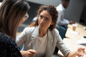 Two professionals in a one-on-one workplace conversation illustrating the human coaching relationship