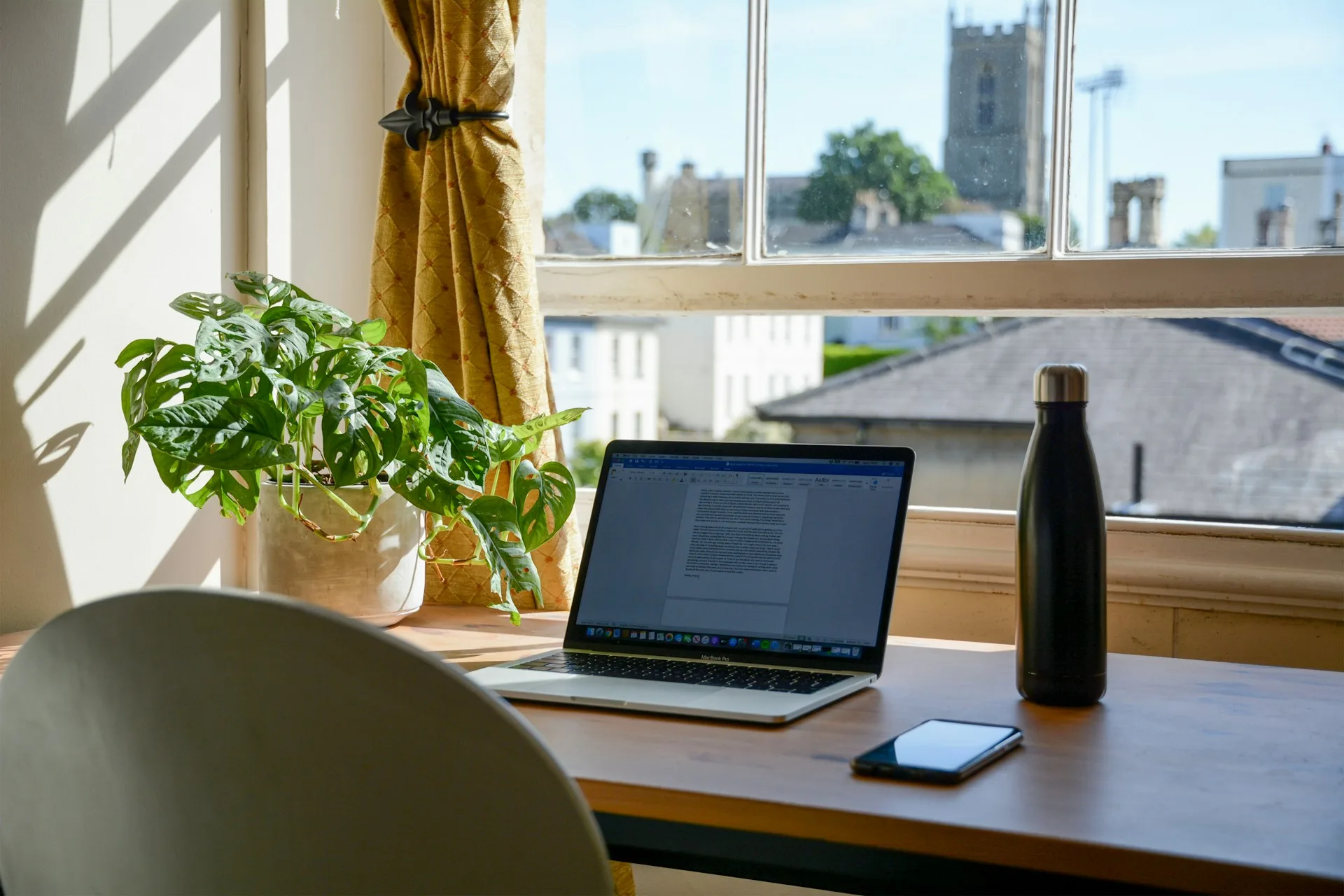 Hybrid employee working from home at a well-lit desk, representing employee wellness programs for hybrid teams