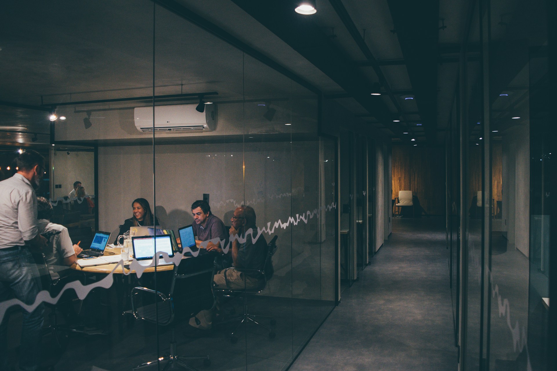 A view through a glass office wall into a workplace meeting, illustrating how vaping in the workplace often goes unnoticed by HR and benefits leaders.