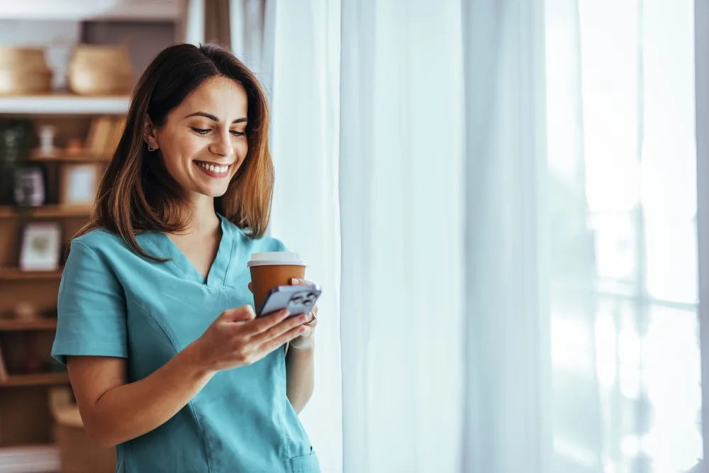 Frontline healthcare worker checking a phone during a short break between shifts