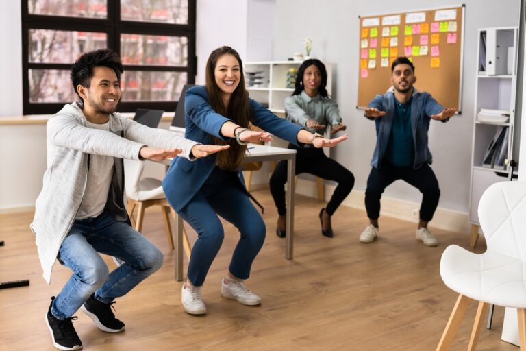 Group of coworkers doing a movement challenge together in their office