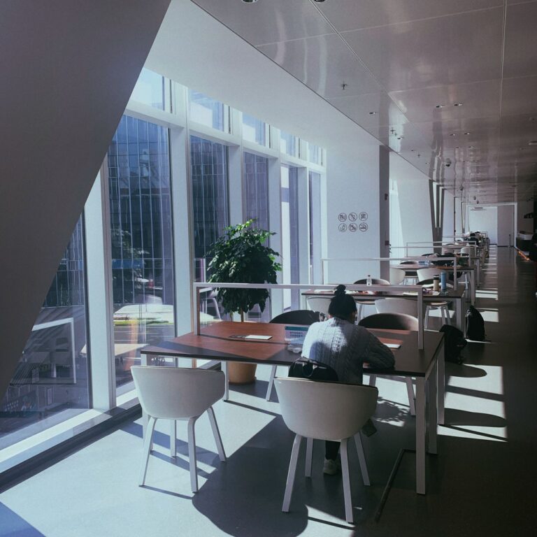 Employee working alone at a sunlit office workspace, illustrating workplace stress and isolation