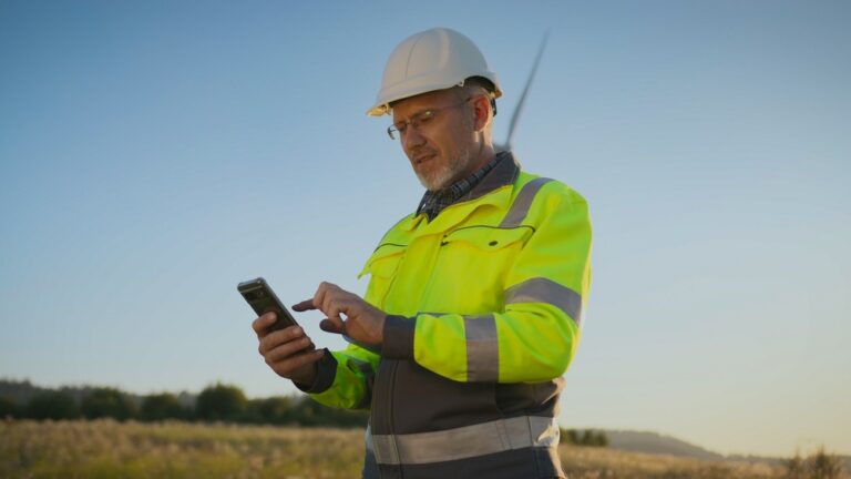 Frontline worker in a hi-vis jacket checking a screening reminder on his phone during a break