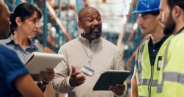 Warehouse supervisor talking with frontline workers during a floor safety conversation