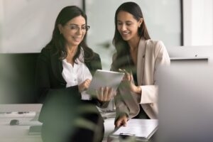 An experienced health coach reviewing member records on a tablet with a newly onboarded coach