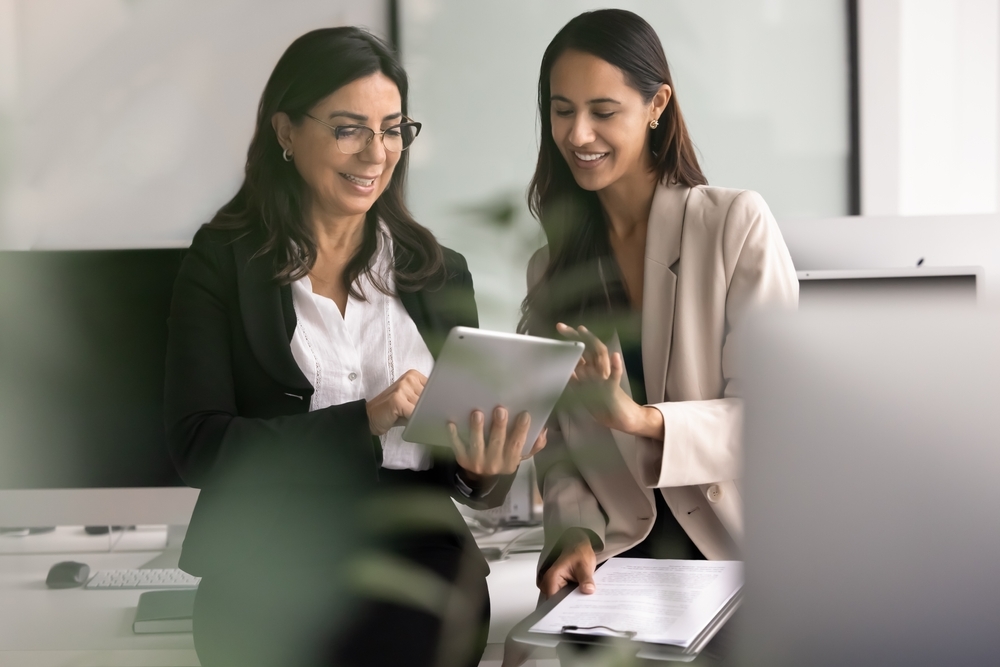 Onboarding a new health coach on the coaching platform An experienced health coach reviewing member records on a tablet with a newly onboarded coach