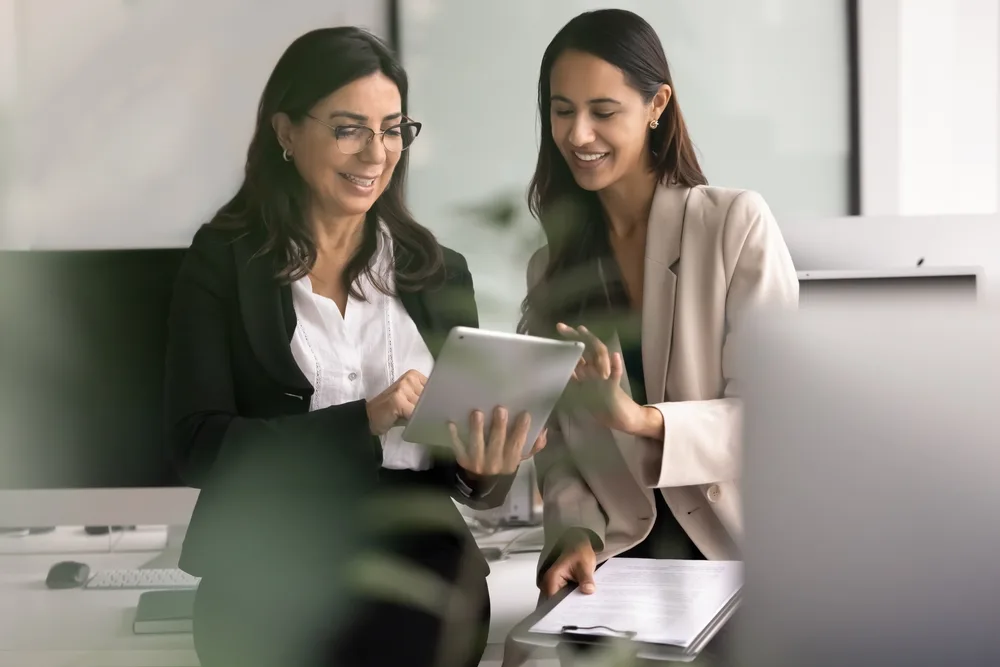 Onboarding a new health coach on the coaching platform An experienced health coach reviewing member records on a tablet with a newly onboarded coach